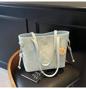 Detalle de un bolso tote verde menta con estampado de mármol y un lindo amuleto de oso