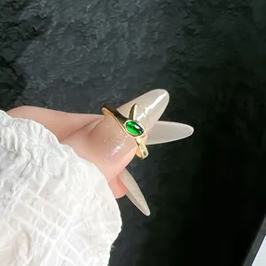 Detailed macro shot of a gold snake-shaped adjustable ring with a vivid green gemstone