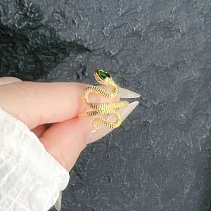 Macro detail of a golden snake-shaped adjustable ring featuring a green gemstone eye.
