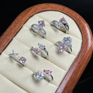 Detailed view of pink and white zirconia open rings in a wooden jewelry display box