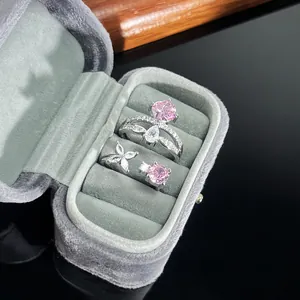 Close-up of two exquisite silver-tone rings with pink and clear zircons in a velvet box.