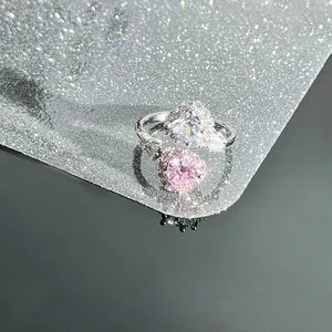 Detailed macro view of an adjustable silver ring with pink and clear heart zircons.