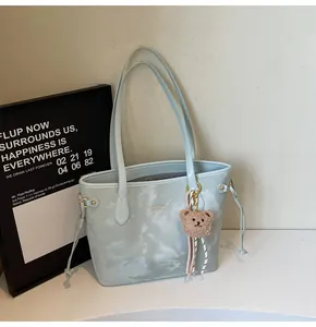 Detalle de bolso tote con estampado de mármol azul y amuleto de oso de peluche