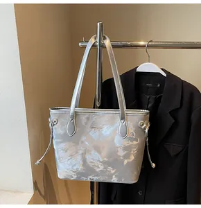 Vista detallada de un bolso tote grande plateado metálico colgado de un perchero de moda