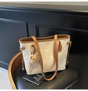 Vista detallada de un bolso tote elegante con estampado de mármol y charm de oso