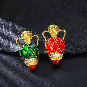 Detailed view of vintage enamel vase brooches in green and red with rhinestone accents