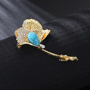 Macro detail of luxury gold ginkgo leaf brooch with turquoise stone and rhinestones