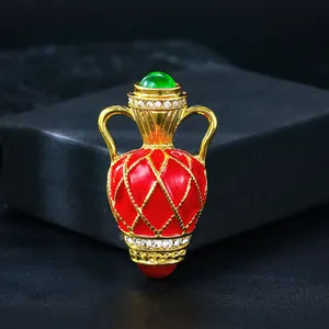 Close-up of luxury vintage red enamel vase brooch with gold plating and sparkling crystals.