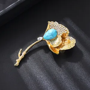 Detail of golden ginkgo leaf brooch with teardrop blue stone and rhinestone inlay