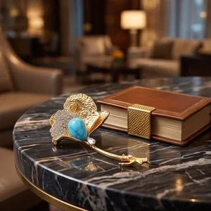 Luxurious gold ginkgo leaf brooch featuring a large turquoise stone on a marble table
