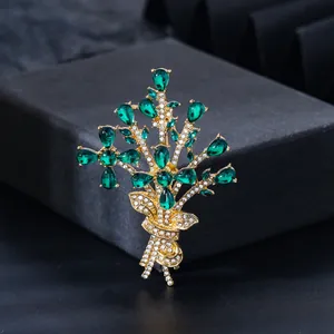 Close-up of emerald green bouquet brooch with gold finish and sparkling crystals