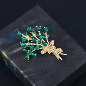 Detail of gold-plated bouquet brooch with emerald green and white crystals on black box