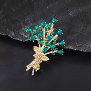 Detailed macro shot of an elegant emerald green floral bouquet brooch with gold finish