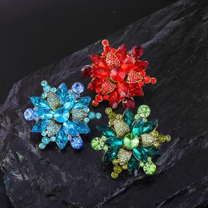 Nahaufnahme von Vintage-Blumenbroschen mit roten, blauen und grünen Kristallen auf Stein.