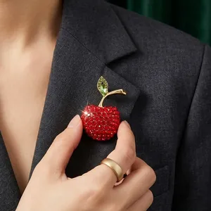 Elegant red rhinestone apple brooch pinned on a dark grey blazer collar.