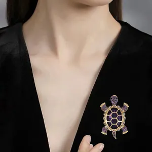 Detailed macro view of the sparkling purple rhinestone turtle brooch on black garment.