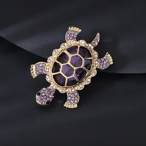 Detailed close-up of a turtle brooch featuring purple crystals and gold-plated finish