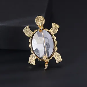 Detailed back view of a gold-tone turtle brooch with a large faceted crystal insert.