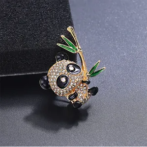 Detail einer funkelnden Panda-Brosche mit Strasssteinen und einem grünen Bambuszweig.