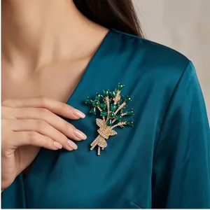 Elegant green crystal flower bouquet brooch pinned on a teal silk dress for women