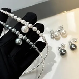 Close-up view of elegant grey and white glass pearl necklaces with matching earrings.