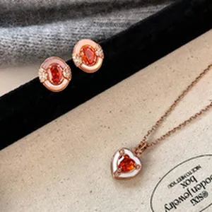 Detail of elegant rose gold jewelry set with red heart pendant and oval studs
