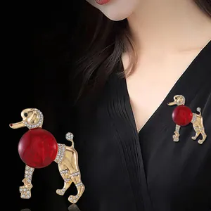 Vue détaillée d'une broche caniche vintage avec boule de verre rouge sur vêtement