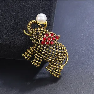 Gedetailleerde close-up van een vintage gouden olifant broche met rode strassteentjes