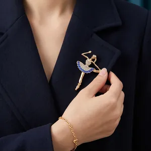 Elegante goudkleurige ballerina broche met blauwe en witte kristallen op een donkerblauwe jas