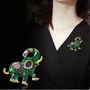 Detailopname van groene emaille olifant speld met kristallen op een zwarte jurk.