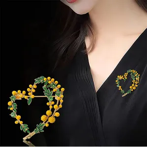 Heart-shaped mimosa brooch with yellow beads and green crystals shown on model's clothing