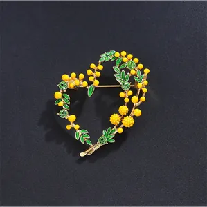 Detailed view of a heart-shaped mimosa brooch with yellow pearls and green rhinestones.