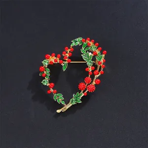 Macro detail of an elegant heart-shaped brooch featuring red berries and green enamel leaves