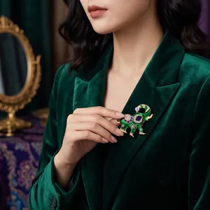 Elegante groene emaille olifantenspeld met kristallen op een fluwelen blazer.