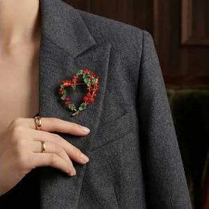 Elegant mimosa fruit heart-shaped brooch with red berries and green leaves on blazer
