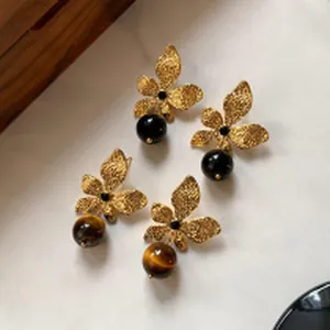 Close-up of vintage palace style golden leaf earrings with tiger eye and black bead drops.
