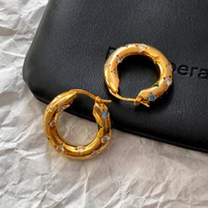 Macro detail showing vintage gold chunky hoop earrings set with vibrant colorful crystals