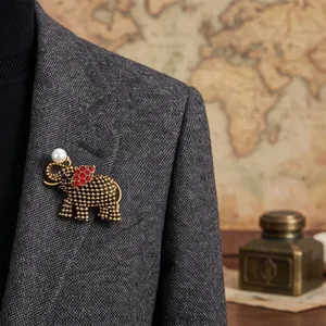 Prachtige vintage olifantenbroche met rode strass en parel op een grijs colbert