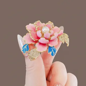 Elegant pink peony flower brooch with a central pearl and crystal-encrusted leaves closeup