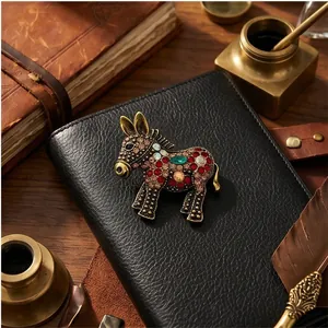 Antique gold donkey brooch with colorful rhinestones on a black leather notebook