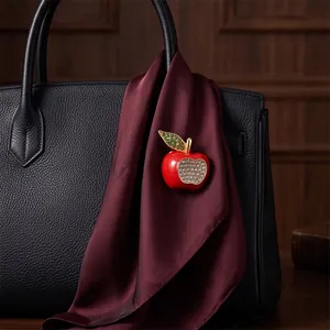 Elegant red enamel apple brooch with clear rhinestones on a burgundy silk scarf