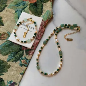 Detailed view of the elegant green stone and pearl jewelry set on a floral background