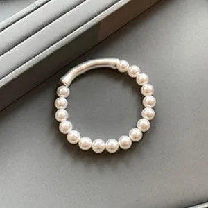 Detailed macro view of minimalist pearl bracelet with elegant curved silver tube segment