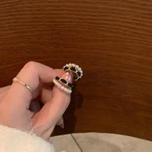 Gros plan d'une bague élégante avec perles et chaîne tressée noire et dorée détaillée