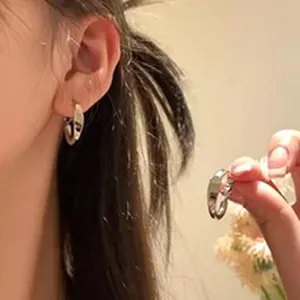 Gros plan détaillé montrant les boucles d'oreilles créoles argentées sur une oreille