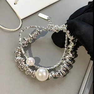 Close-up of irregular silver nuggets and white pearls on a minimalist chain bracelet