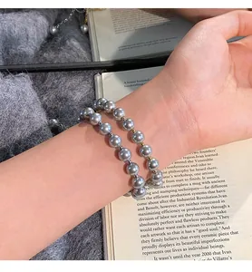 Detailed macro shot of grey glass pearl bracelets on wrist with 24k gold plating details