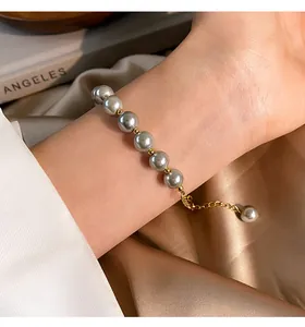 Detailed view of elegant grey glass pearl bracelet with gold plated chain on wrist