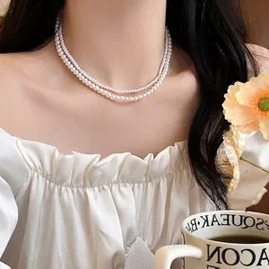 Elegant double-strand white pearl necklace worn by a model in a cozy cafe setting