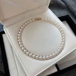 Detailed macro shot of elegant white pearl necklace with gold clasp in jewelry box